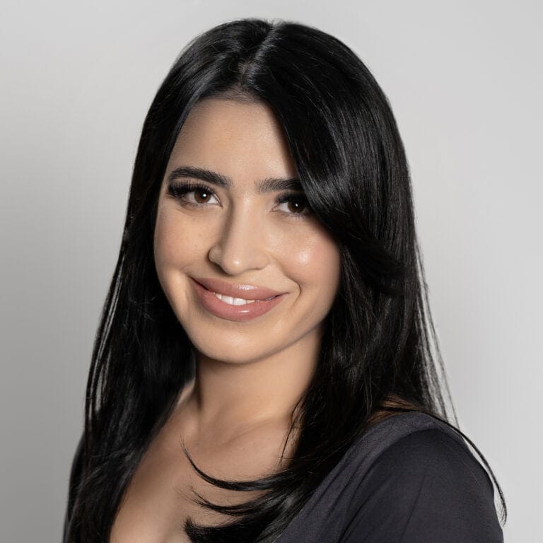 Professional Real Estate Agent, Tamara Navarro, with long black hair smiling confidently, representing mastery and expertise in her field, suitable for SEO keywords related to mastery and professional success.