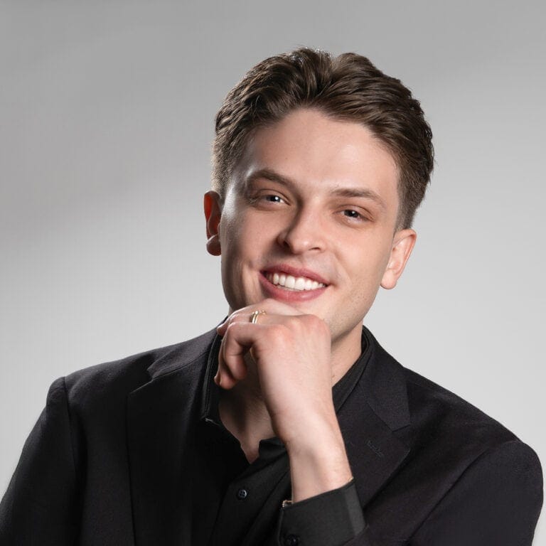 A smiling Real Estate Agent, Ethan Hayes, man in a black suit, representing confidence and professionalism, with a focus on mastery and expertise in his field.