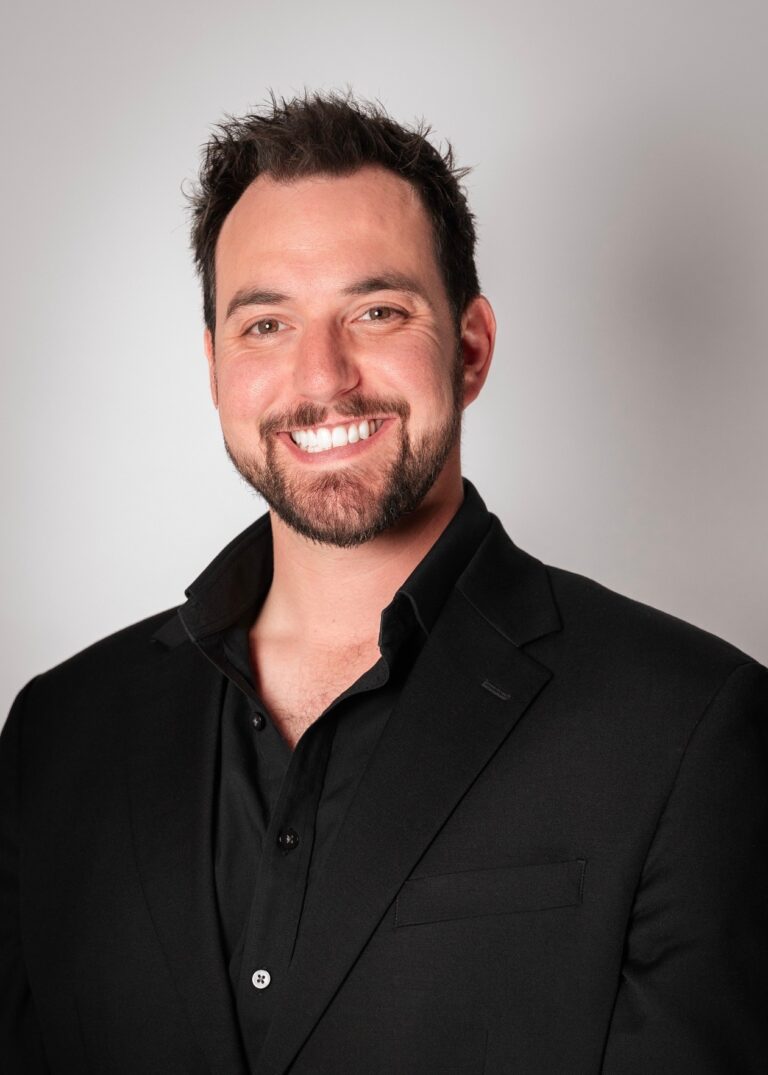 Professional portrait of Brendan Burdock, Albuquerque real estate expert, smiling in a black suit for real estate marketing.