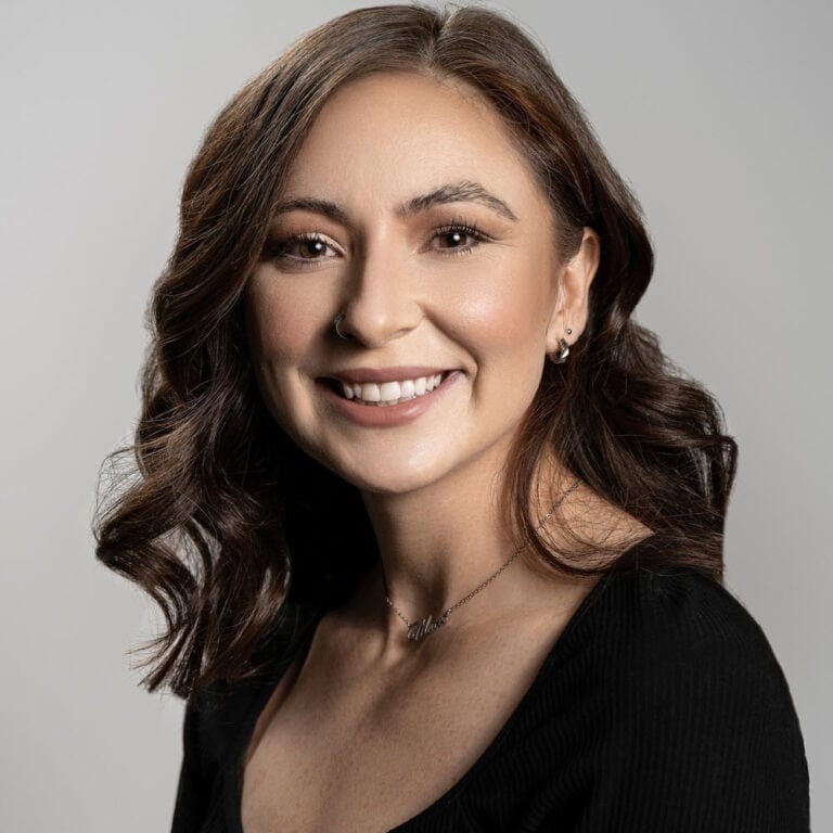 Professional portrait of a confident Real Estate Agent, Marisshia Sigala, with long, wavy brown hair, smiling warmly, wearing a black top, showcasing beauty and self-assurance, ideal for personal branding or professional profiles.